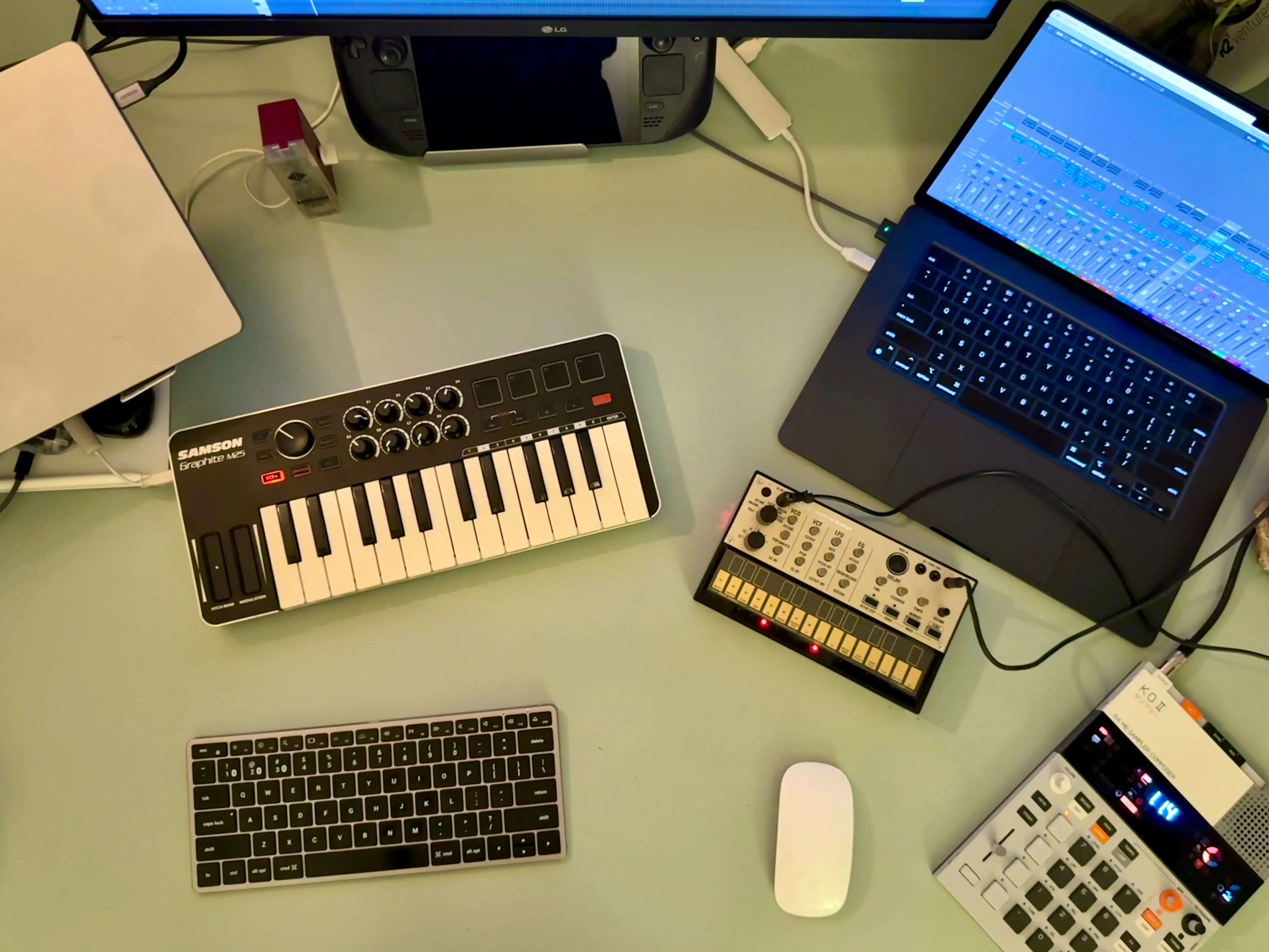 Uma foto de cima de uma mesa com instrumentos tipo teclados e um computador laptop